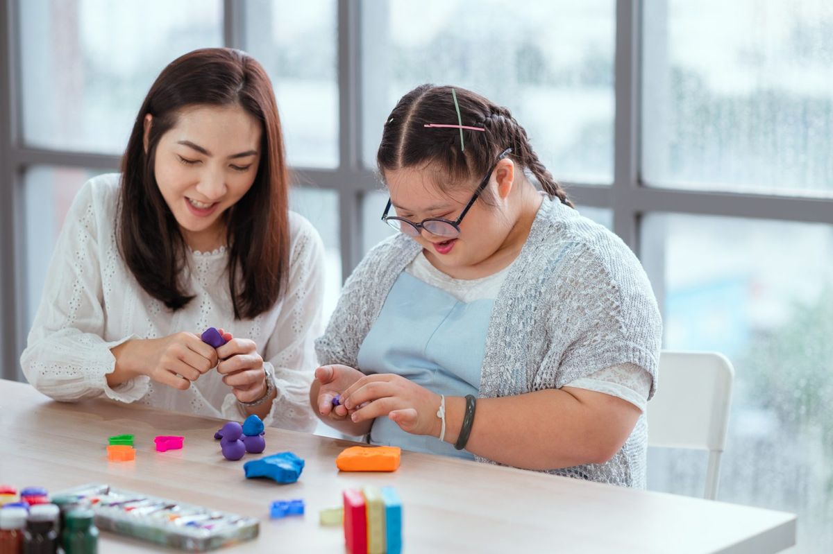 Two women work together on a hands-on project at a table.