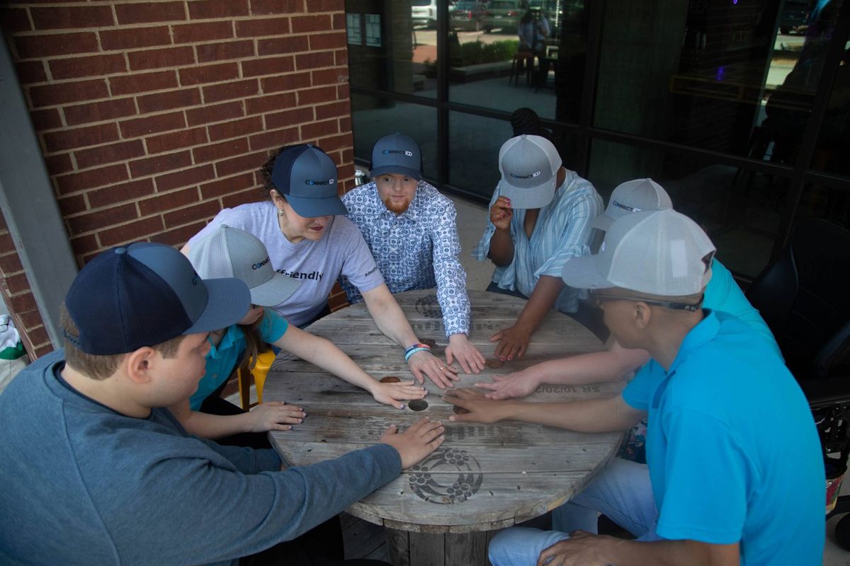 A group of young men stack hands at a table.
