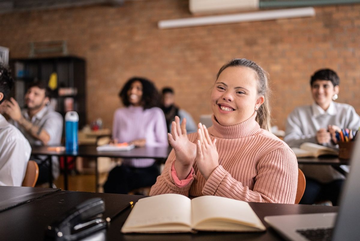 A smiling student claps in a classroom.